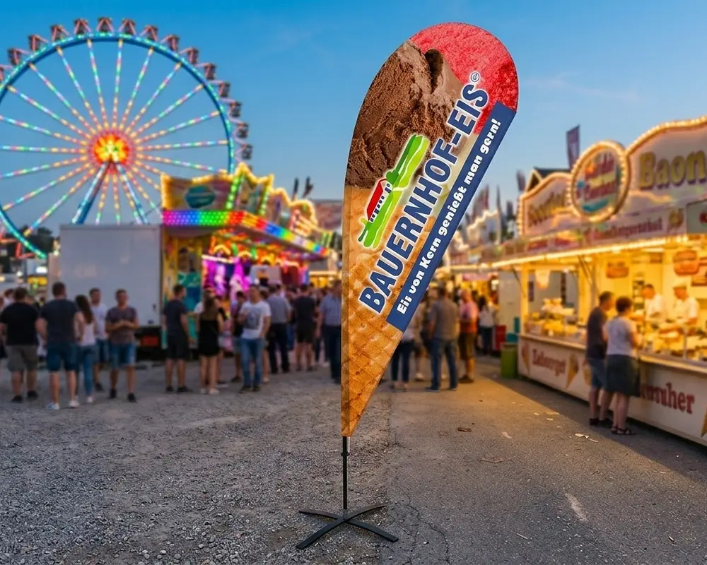 Hochwertige Beachflag in Tropfenform (Beachflag Drop) für Bauernhofeis Kern auf einem Volksfest – mobiles Werbesystem mit stabilem Kreuzfuß.