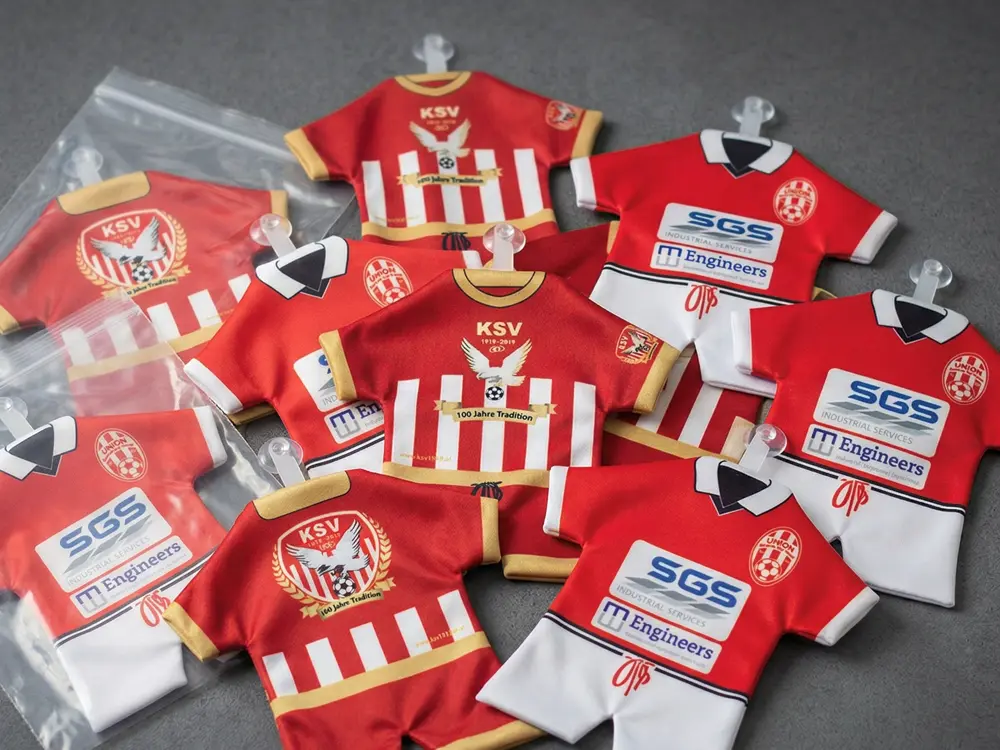 Individuell bedruckte Mini-Fußballtrikots mit detailgetreuem Vereinslogo und Sponsoren-Branding als geniales Fan-Merchandising für Fußballvereine und Clubs.
